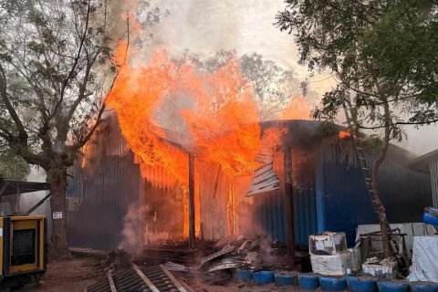 En brinnande byggnad med två människor i förgrunden.