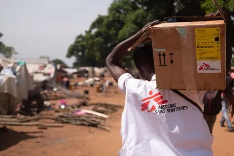 Person i MSF-väst bär en kartong på axeln