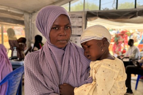 Kvinna håller i barn med bandage runt huvudet