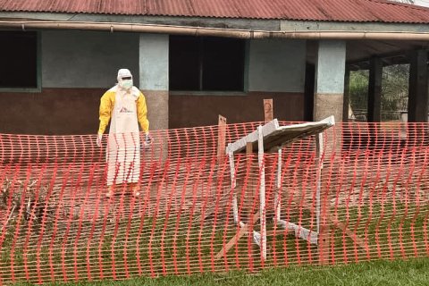 Person i MSF-skyddsdräkt utanför en byggnad