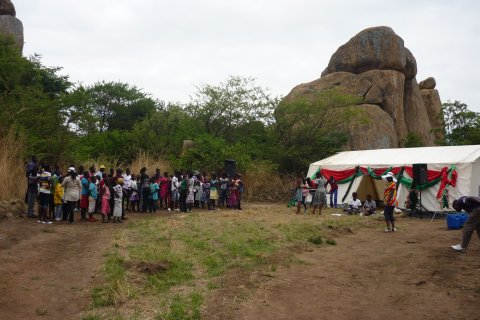 En stor grupp människor står bredvid ett partytält