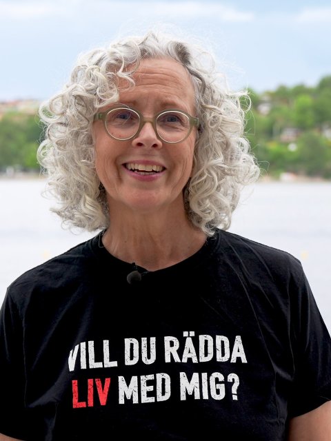 Leende kvinna vid vatten med en Läkare Utan Gränser t-shirt