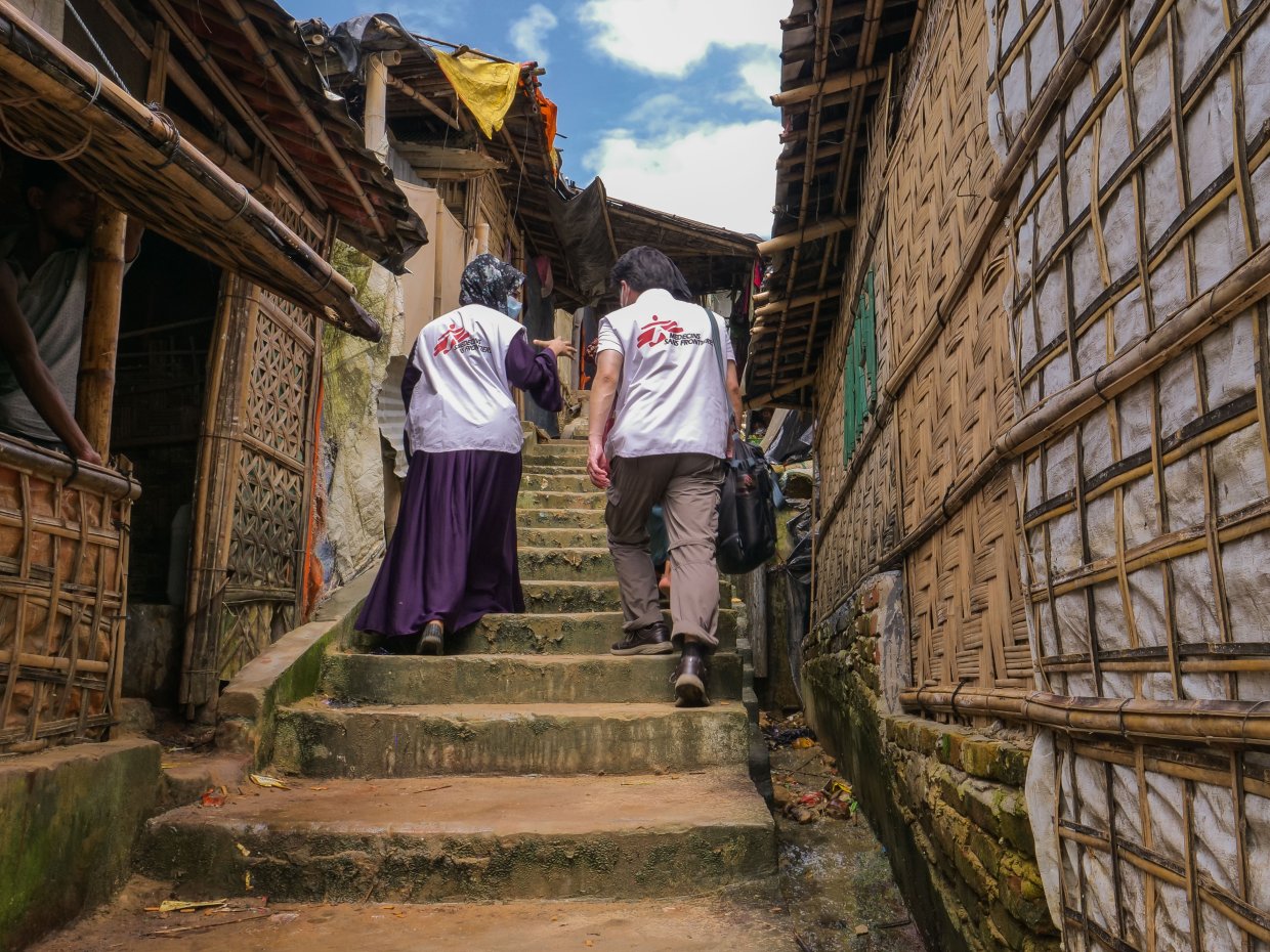 Två medarbetare med Läkare Utan Gränsers logga på ryggarna går upp för en trappa i Cox's Bazar.