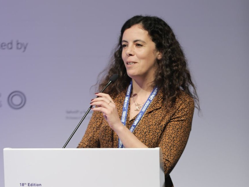 En kvinna står i en talarstol på en konferens.