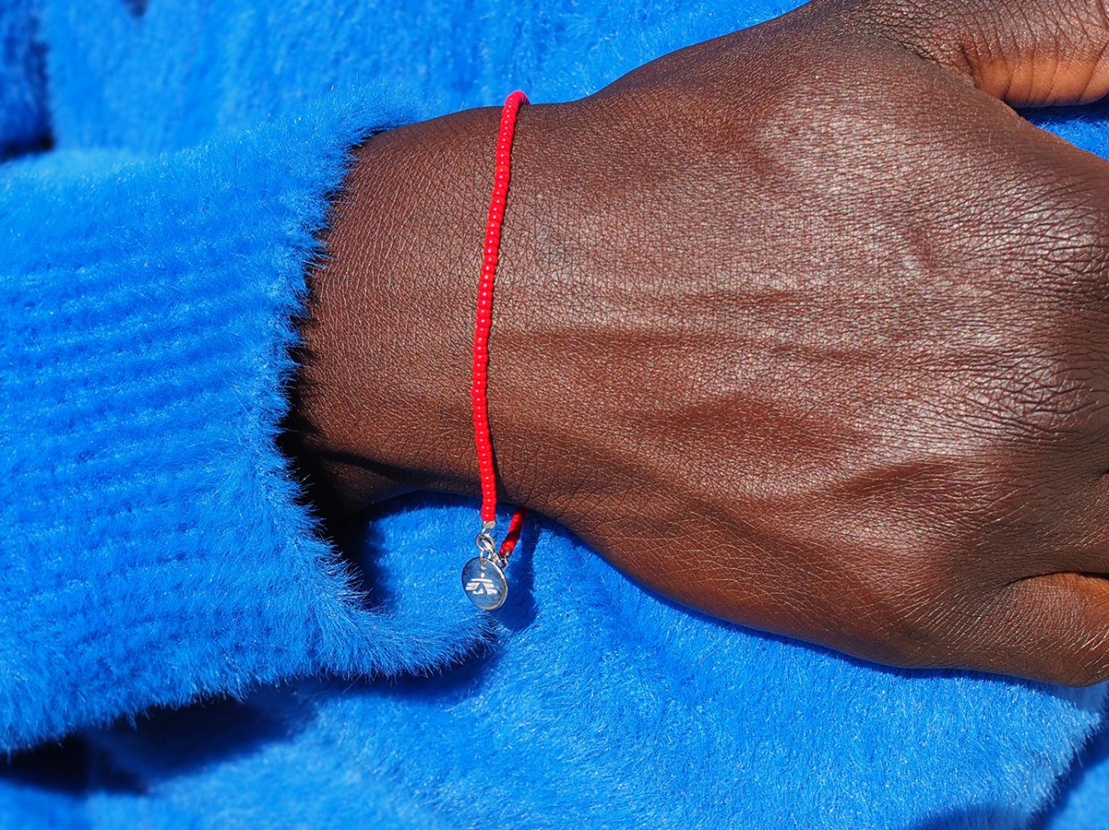 Ett rött armband på en person med blå tröja.