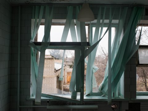 Gardiner fladdrar i ett trasigt fönster.