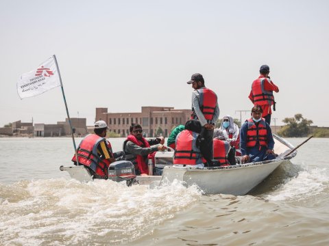 En båt med personal från Läkare Utan Gränser och dess flagga längst bak åker fram i ett översvämmat landskap.
