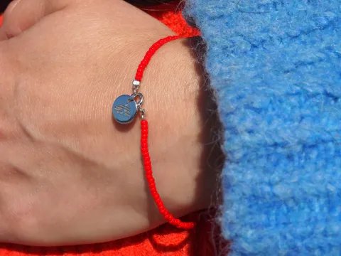 Ett rött pärlarmband på en arm med en tjocktröja