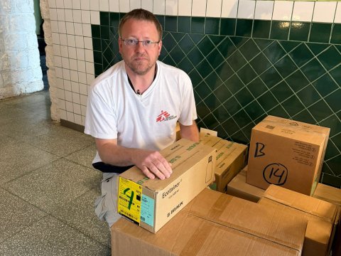 En man sitter vid ett par lådor och tittar in i kameran.