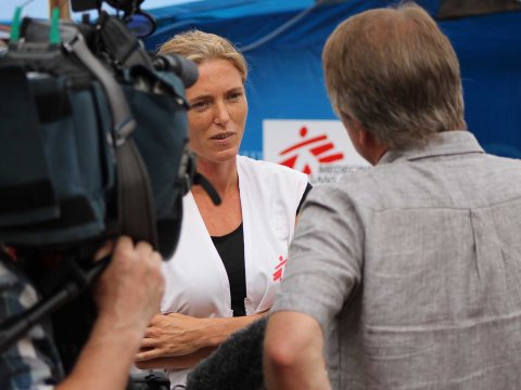 En kvinna i Läkare Utan Gränser-väst intervjuas av en journalist och en kameraman.