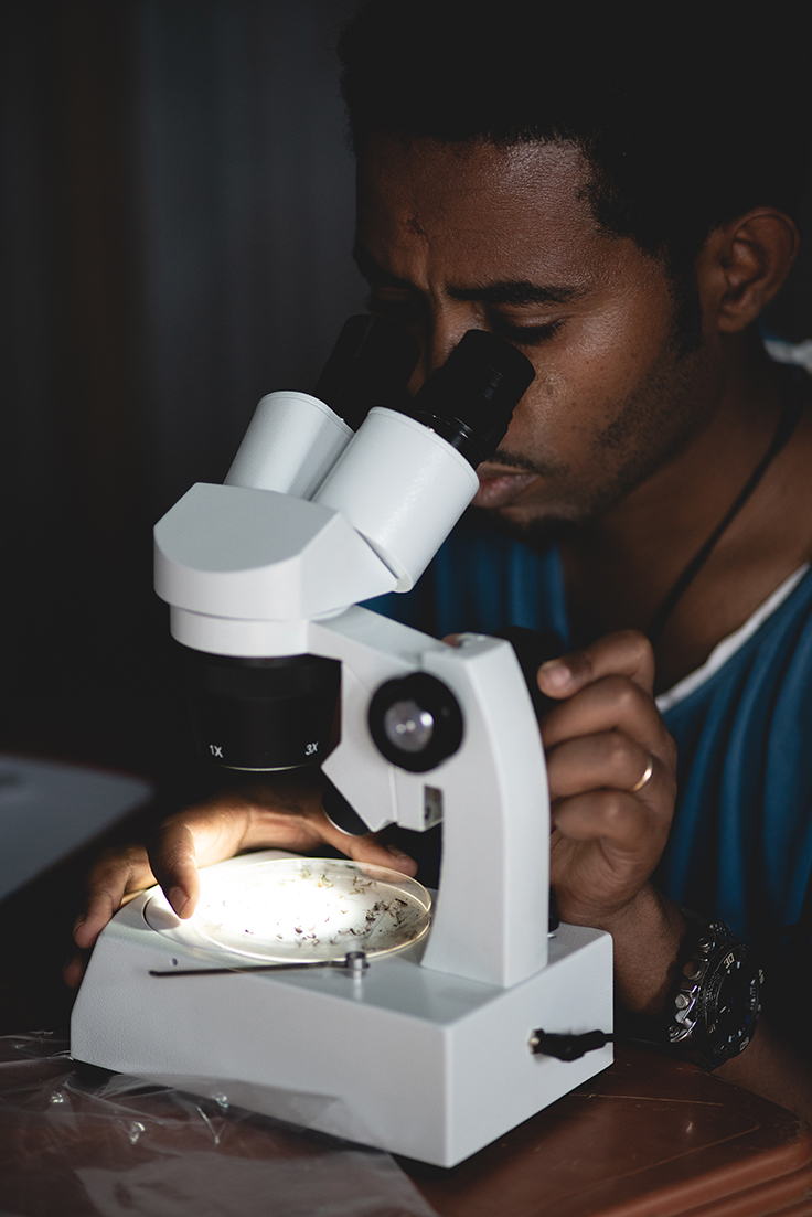 En man tittar i ett mikroskop